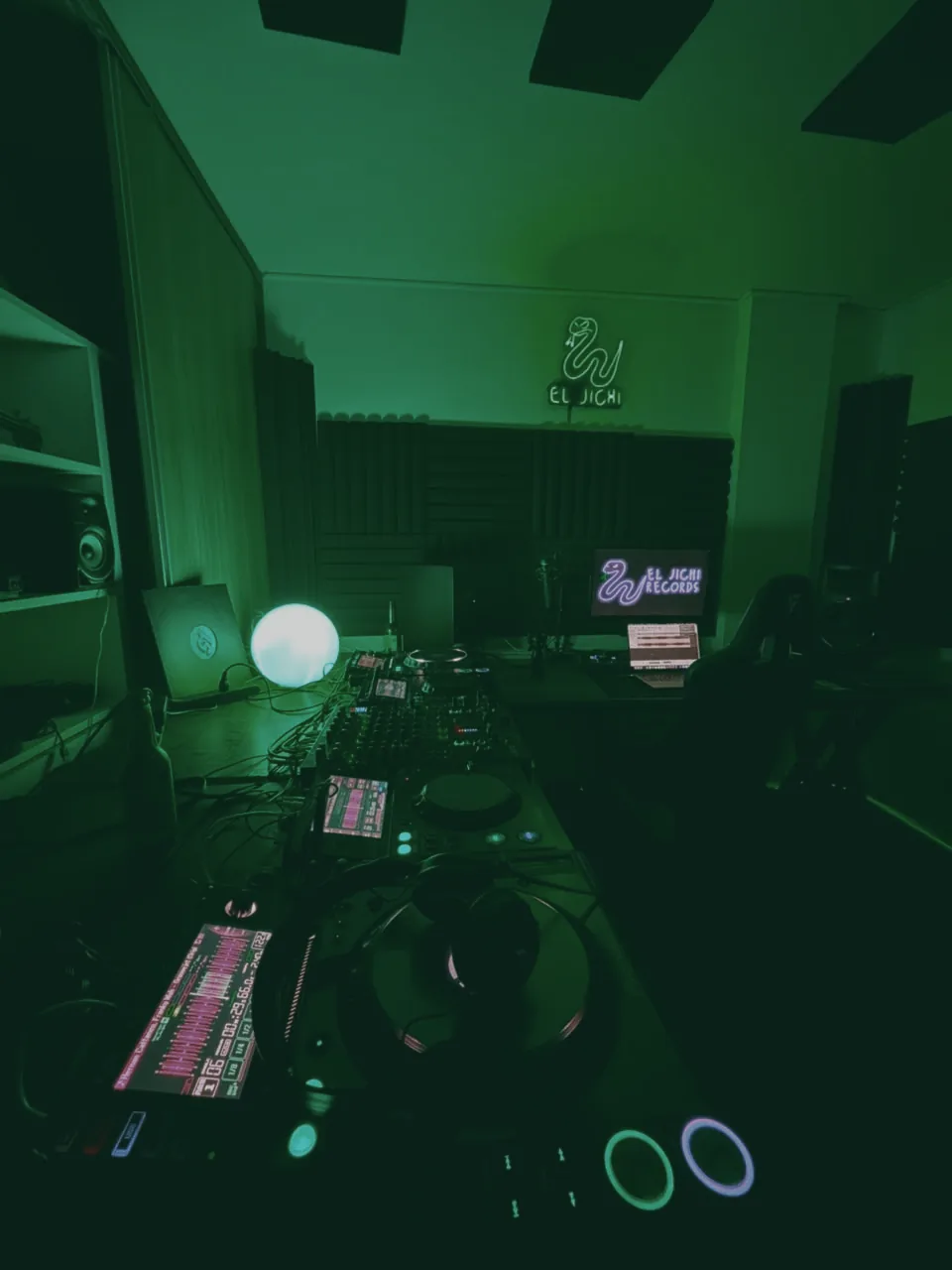 Cabina de DJ de El Jichi con la mesa de producci&oacute;n y el letrero de ne&oacute;n al fondo